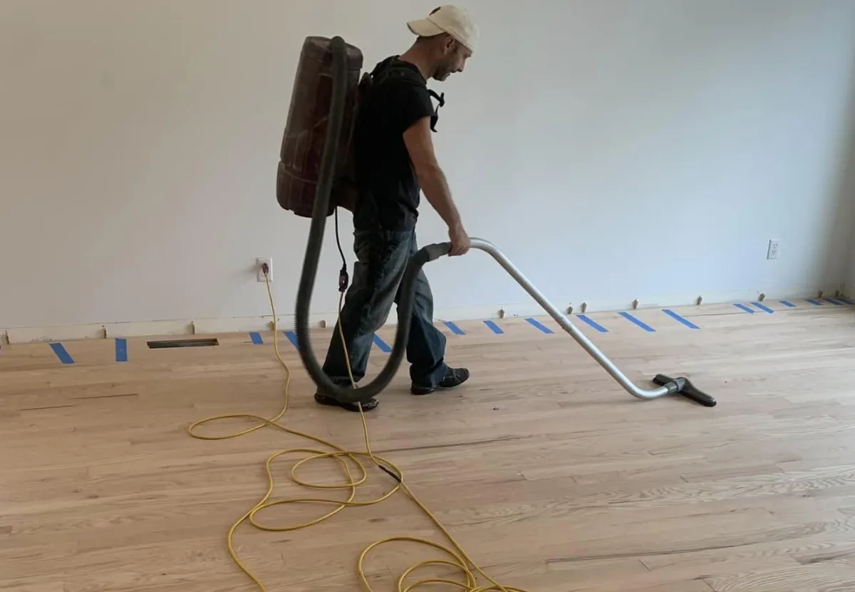 Worker using equipment to sand hardwood flooring indoors