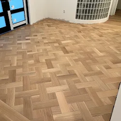 Wood parquet flooring in herringbone pattern in empty room with windows