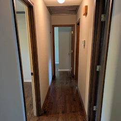 Narrow hallway with hardwood floors and multiple doorways with dark frames