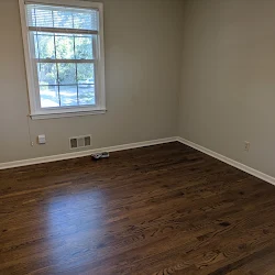 Empty room with hardwood floor, large window, and white walls