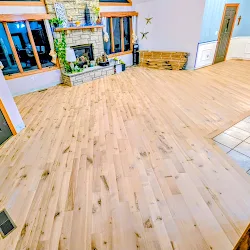 Spacious wooden flooring installation in bright showroom with blue-framed windows and product displays