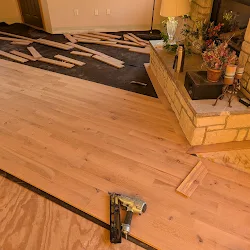 Hardwood flooring installation in progress with tools and materials on wooden subfloor
