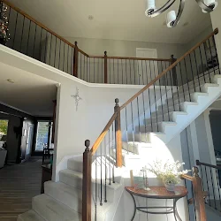 Modern staircase with metal railings and wooden handrail in bright entryway
