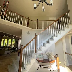 Modern two-story foyer with curved staircase, white railings, and natural light from front door