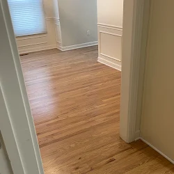 Hallway with wood laminate flooring, white walls, and baseboards