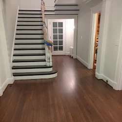 Spacious entryway with wooden flooring, staircase, and glass doors