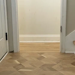 Empty room with herringbone wood flooring and white walls