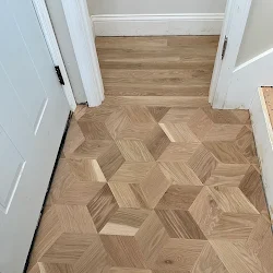 Herringbone wood flooring in entryway with white trim and doorways