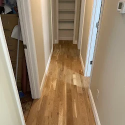 Narrow hallway with wooden hardwood flooring and white walls with open doorways