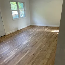 Empty room with hardwood flooring, white walls, and window with natural light