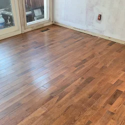 Empty room with newly installed hardwood flooring and white walls