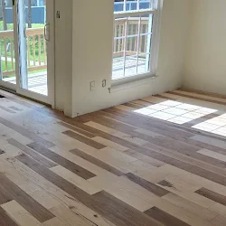 Empty room with mixed-width hardwood flooring and glass doors opening to balcony