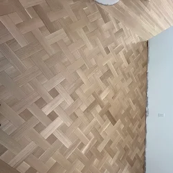 Herringbone pattern wood flooring installation in neutral tan tones