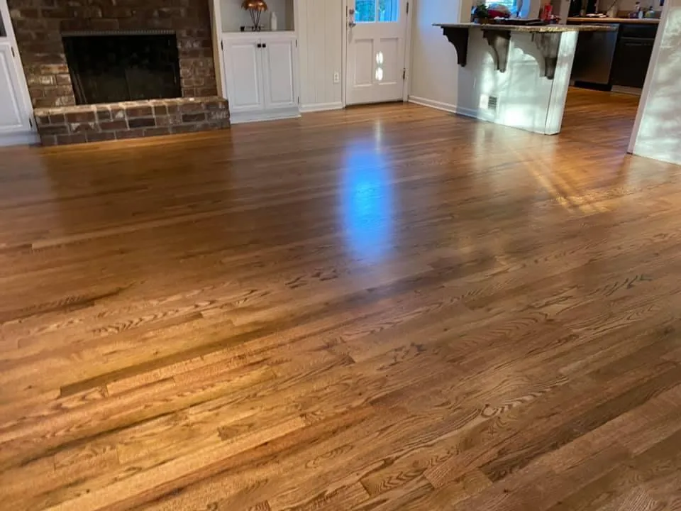 Polished hardwood floor in open living room with fireplace and kitchen island
