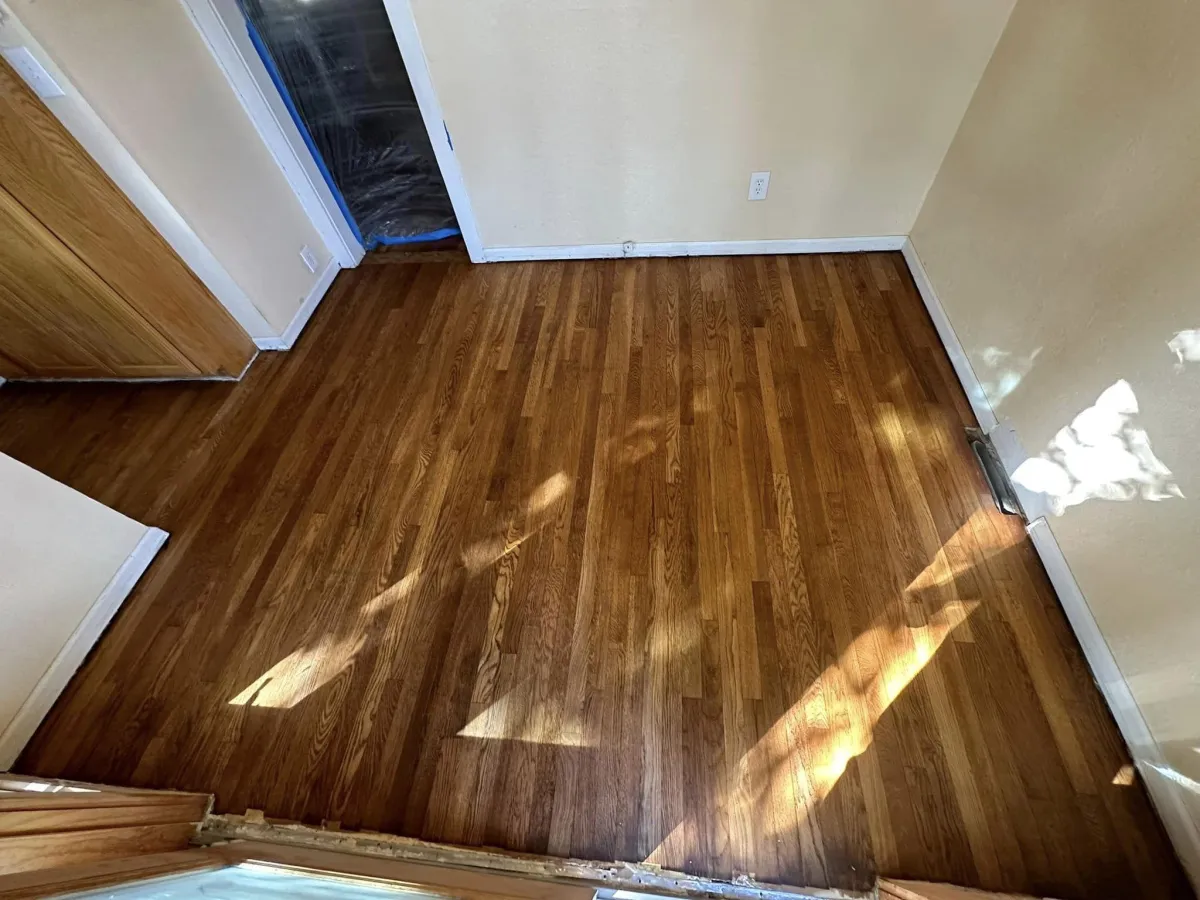 Empty room with hardwood flooring and white walls with natural light streaming through windows